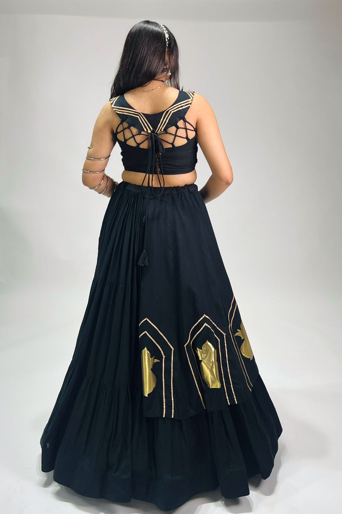 Back view of black chaniya choli with dori blouse closure and golden lehenga work