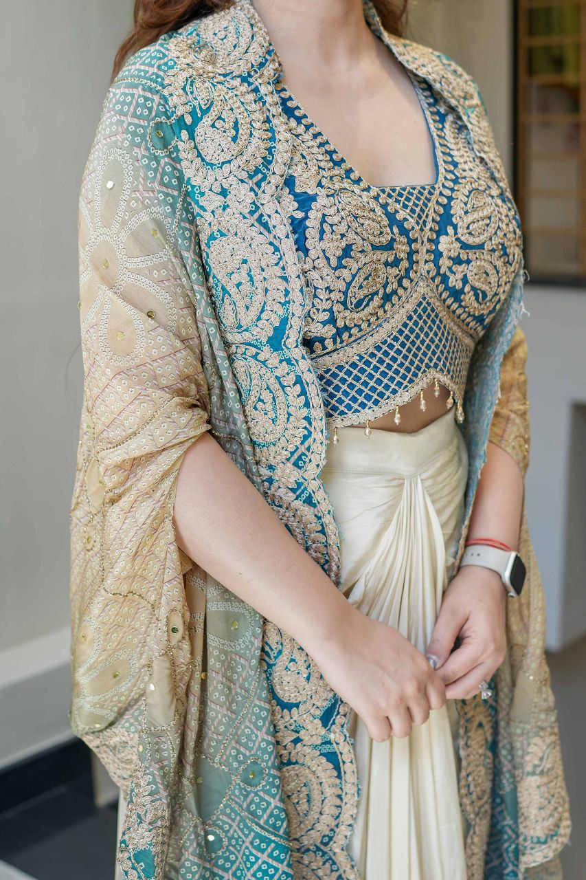Blue-teal embroidered blouse and Bandhani print shrug styled with an Indo Western dhoti
