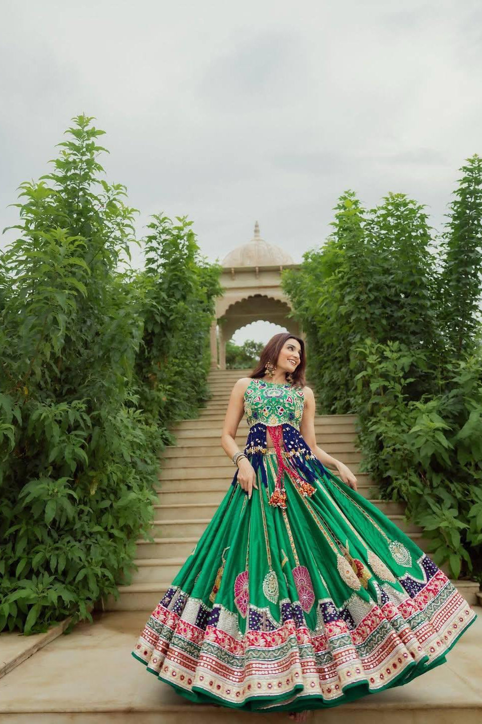 Green Indian ethnic lehenga choli styled against a palace-inspired outdoor setting