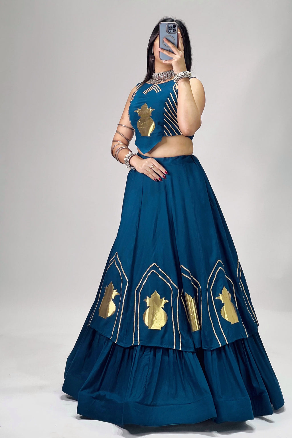 Side view of teal blue Chitra Chaniya Choli with tiered lehenga and golden patch work