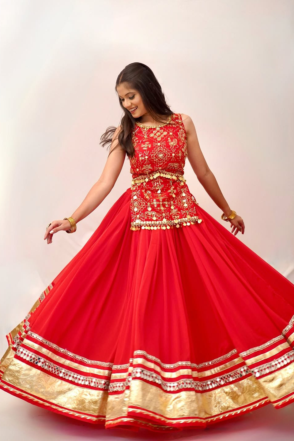 Red Indian lehenga choli shown in a flowing twirl with detailed gold lace border